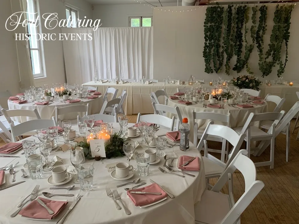 Round tables set for a Winnipeg wedding reception at St Norbert Arts Centre with white linens, candles, and floral details